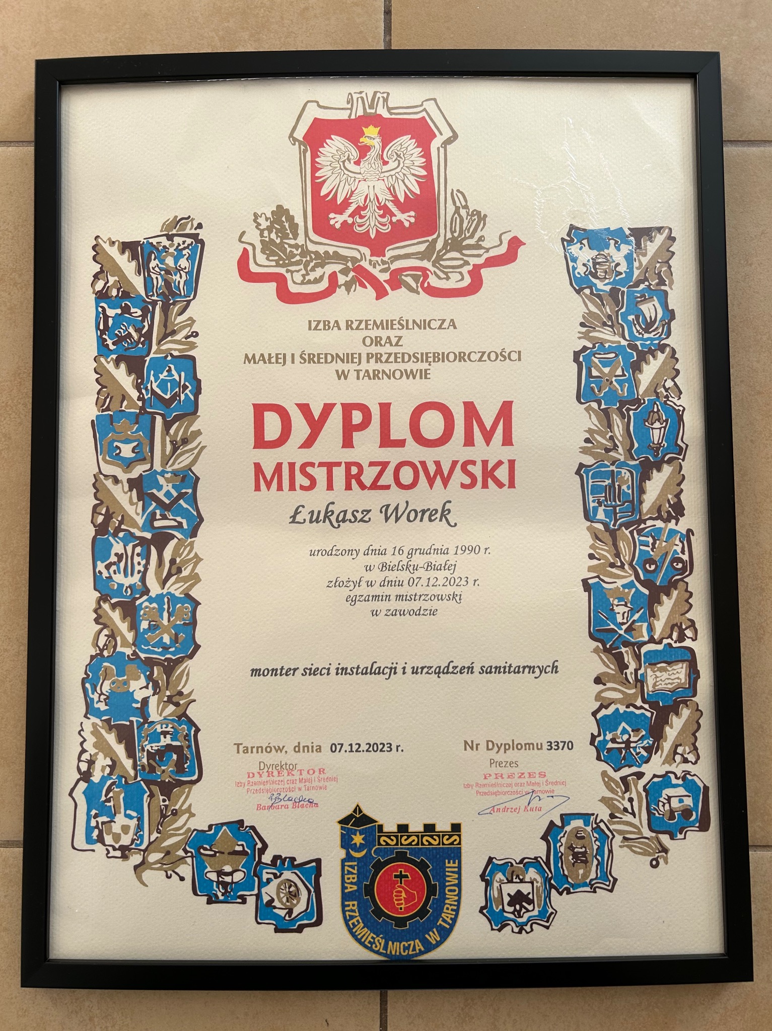 Dyplom mistrzowski dla Łukasza Worka, montera sieci instalacji i urządzeń sanitarnych, wydany przez Izbę Rzemieślniczą w Tarnowie, oprawiony w czarną ramę.
