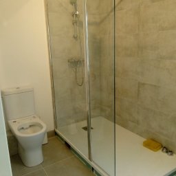 Łukasz - Wykończona łazienka z kabiną prysznicową typu walk-in, beżowe płytki, biała toaleta. Widoczne detale wykończeniowe i akcesoria łazienkowe.