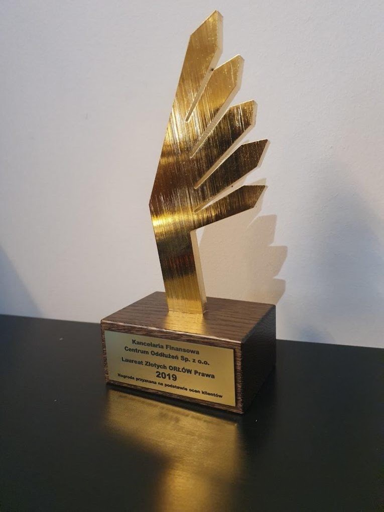Złota statuetka 'Laureat Złotych Orłów Prawa 2019' na ciemnym blacie. Nagroda przyznana na podstawie ocen klientów dla Kancelarii Finansowej.