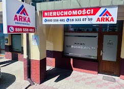 Fasada biura nieruchomości ARKA z widocznym logo i numerami telefonów. Ujęcie z zewnątrz, w słoneczny dzień. Charakterystyczna kolorystyka i branding firmy.