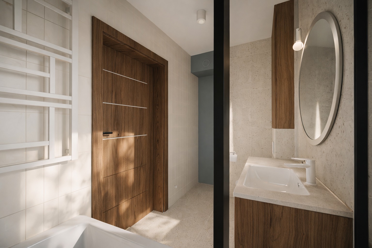 Nowoczesna łazienka z drewnianymi akcentami: drzwi z poziomymi paskami, owalne lustro i biała umywalka na tle beżowych płytek. Minimalistyczny design.