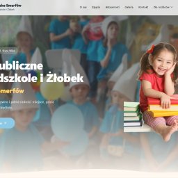 Mozart Way - Strona internetowa przedszkola i żłobka 'Wioska Smerfów' z uśmiechniętą dziewczynką z książkami na pierwszym planie i dziećmi w tle. Jasna kolorystyka, przyjazny design.