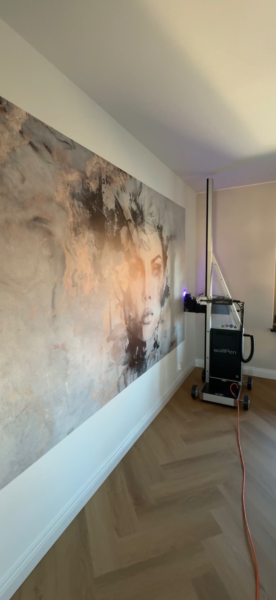 Wnętrze z parkietem i ścianą ozdobioną portretem kobiety, naniesionym za pomocą urządzenia WallPen. Nowoczesna technika dekoracji ścian.