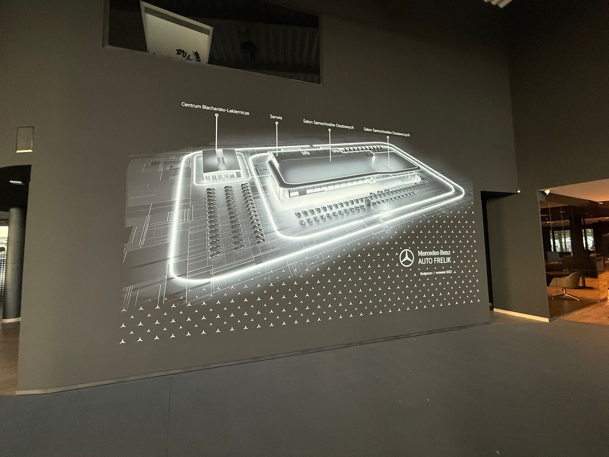 Grafika na ścianie przedstawiająca plan salonu Mercedes-Benz Auto Frelik z podziałem na Centrum Blacharsko-Lakiernicze, Serwis i Salony Samochodów. Bydgoszcz, wrzesień 2023.