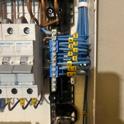 Mariusz K - Rozdzielnica elektryczna z podłączonymi przewodami oznaczonymi numerami, widoczne zabezpieczenia Hager. Detal instalacji wewnątrz skrzynki.