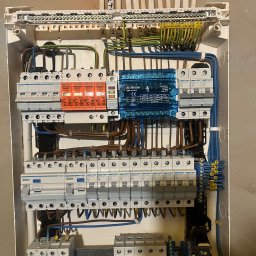 Mariusz K - Rozdzielnica elektryczna z zainstalowanymi zabezpieczeniami, widoczne przewody i oznaczenia. Elementy Hager i Ergom. Instalacja wewnątrz budynku, widok z bliska.