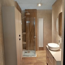 BUDREM OLHA MOROZ - Nowoczesna łazienka z kabiną prysznicową typu walk-in, umywalką nablatową i wysoką szafką. Neutralna kolorystyka, drewnopodobne płytki na podłodze, grzejnik drabinkowy.