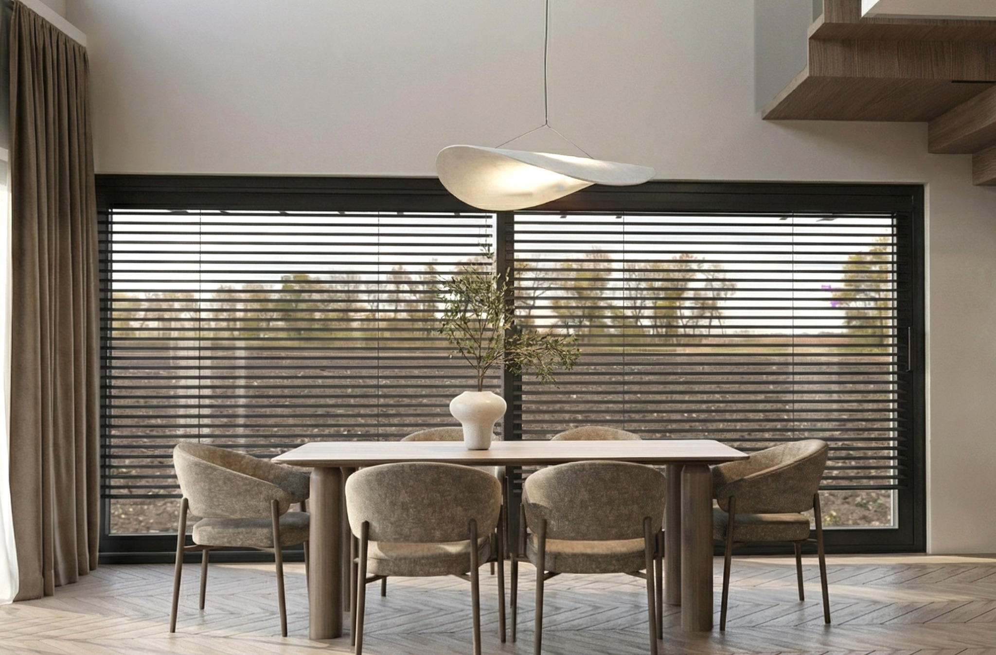 Nowoczesna jadalnia z drewnianym stołem, krzesłami w odcieniach szarości i oryginalną lampą. W tle okno z żaluzjami i widok na zieleń. Minimalistyczny design.