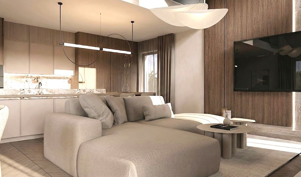 Nowoczesny salon z beżową sofą modułową, okrągłym stolikiem kawowym i minimalistycznym oświetleniem. Drewniane panele ścienne i marmurowy blat kuchenny w tle.