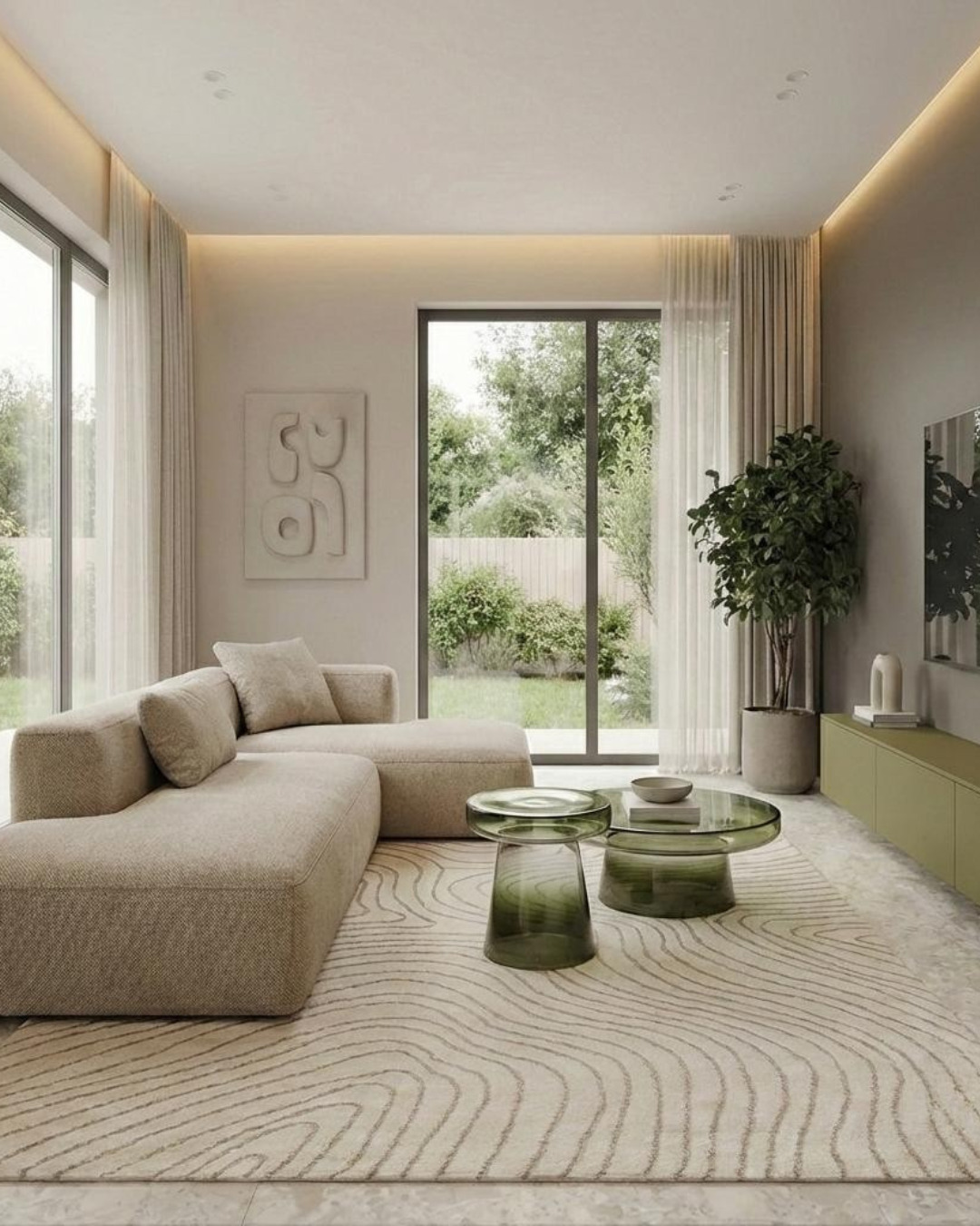 Jasne wnętrze salonu z beżową sofą modułową, szklanymi stolikami i wzorzystym dywanem. Duże okna z widokiem na ogród wpuszczają naturalne światło.