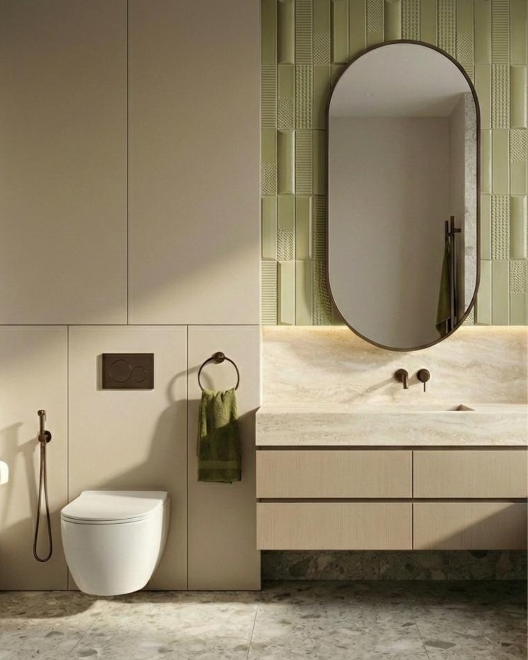 Elegancka łazienka w beżach i zieleni z owalnym lustrem, wiszącą toaletą i marmurową umywalką. Minimalistyczny design z akcentami w kolorze brązu.