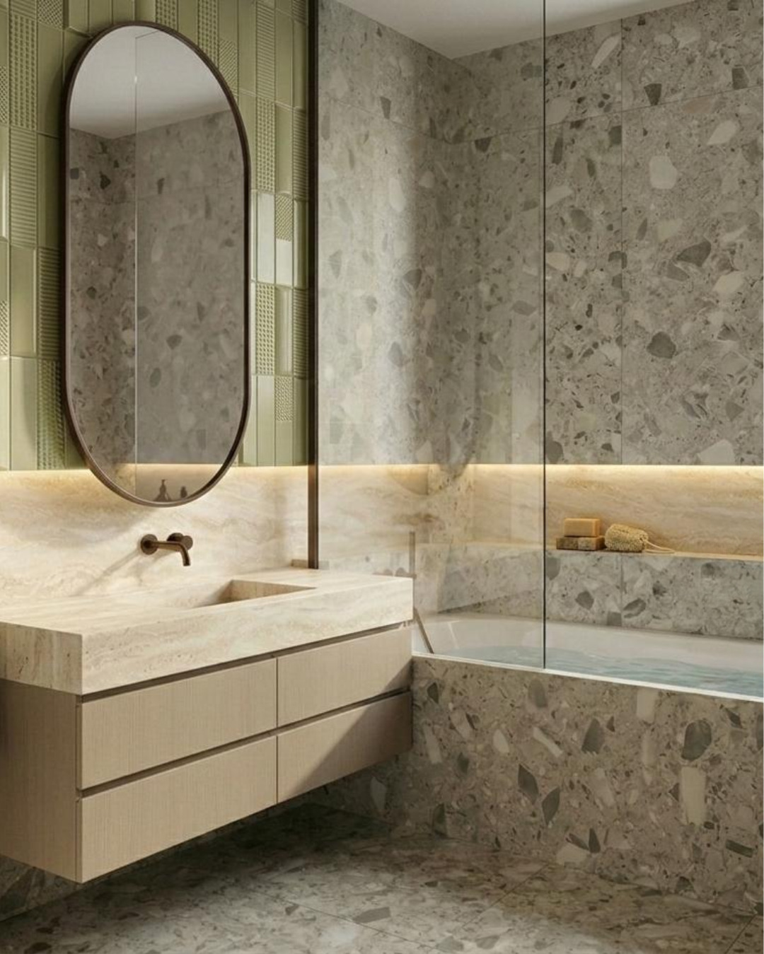 Nowoczesna łazienka z umywalką nablatową, owalnym lustrem i płytkami imitującymi lastryko. Podświetlenie LED dodaje ciepła wnętrzu.