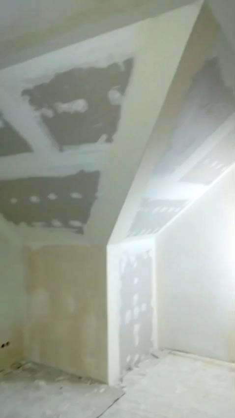 Skośne poddasze po szpachlowaniu w Perzowie. Widoczne fragmenty płyt karton-gips z nałożoną gładzią, przygotowane do malowania. Ściany w trakcie wykańczania.