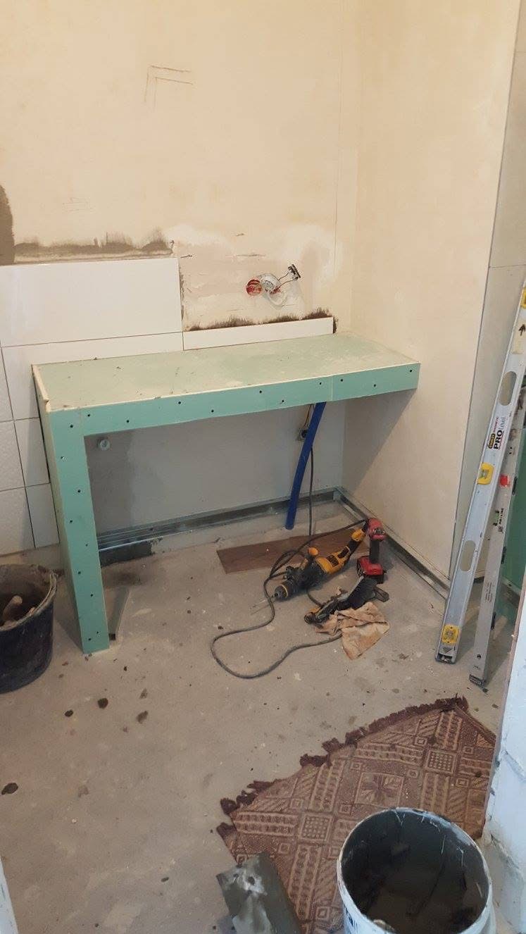 Wnęka pod umywalkę z płyty GK w trakcie remontu łazienki w Gdańsku. Widoczne narzędzia i fragment ułożonych płytek. Prace wykończeniowe w toku.