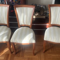 SofaClinic - Cztery krzesła z drewnianą ramą i tapicerką w kremowe pasy, ustawione na parkiecie. W tle komoda i klatka dla gryzonia z tunelem.