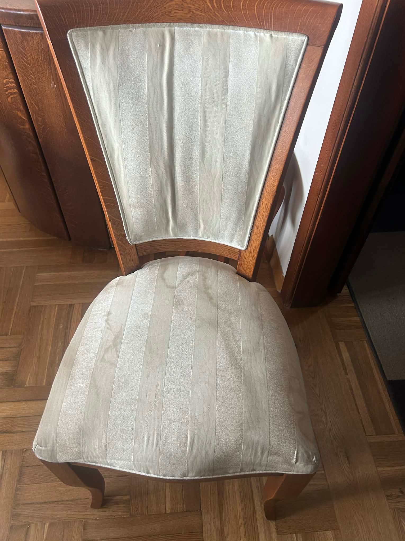 Krzesło z drewnianą ramą i tapicerowanym siedziskiem w paski, ustawione na parkiecie. Widok z góry, ukazujący detale tapicerki i konstrukcji krzesła.