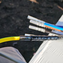 Denys Modelskyi 'DKSSystem' - Połączenie kabla ochronnego żółto-zielonego z czarną termokurczką, widoczne złącza i narzędzia na ciemnym tle. Precyzyjne wykonanie.