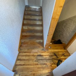 Perfect Wall - Drewniane schody w trakcie renowacji, widoczne ślady cyklinowania i narzędzie pracy. Parkiet na podłodze z wyraźnymi śladami użytkowania. Widok z góry.