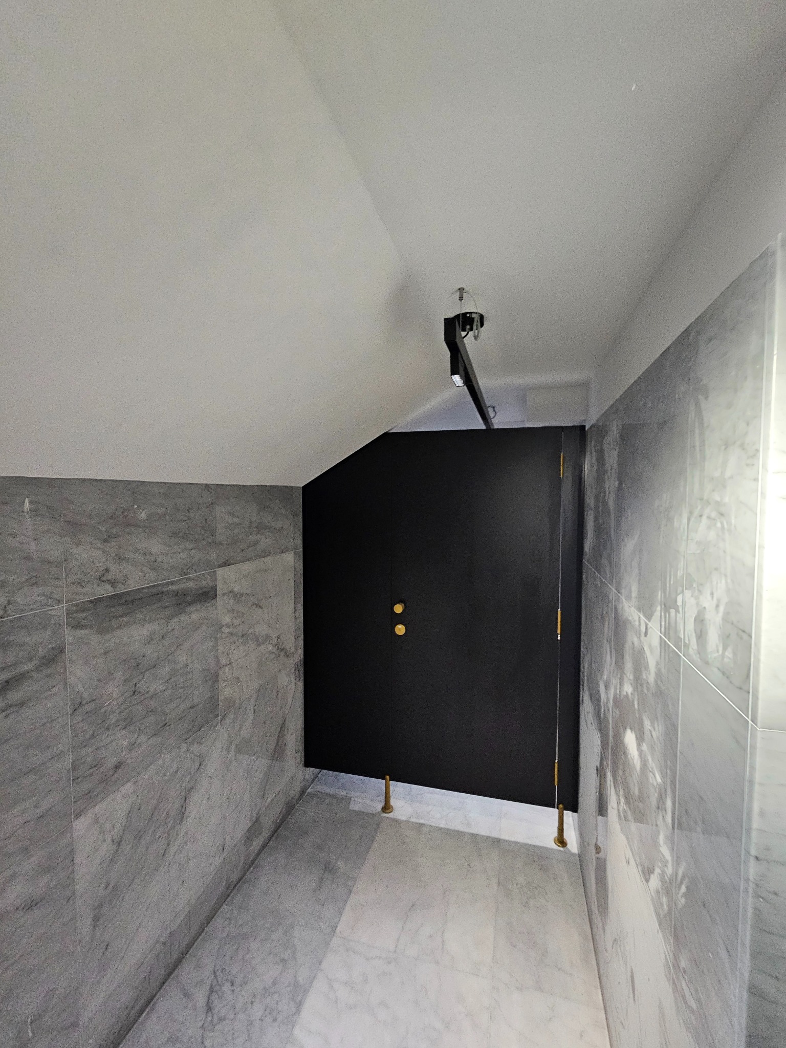 Nowoczesna łazienka z marmurowymi płytkami i czarnymi drzwiami. Minimalistyczny design, złote akcenty. Wykończenie z dbałością o detale.