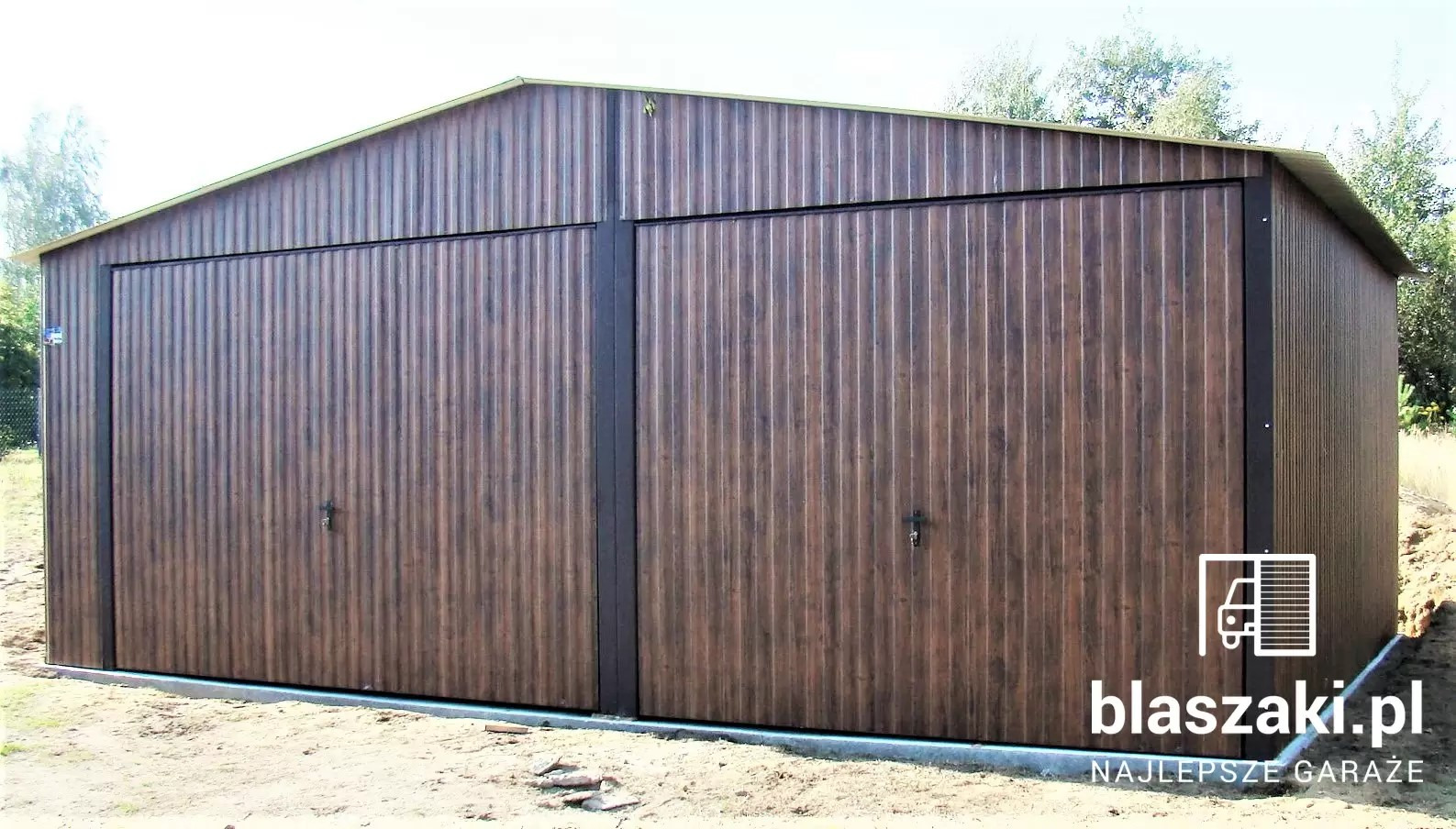 Dwustanowiskowy garaż blaszany w odcieniach brązu, z dwuspadowym dachem i czarnymi elementami konstrukcyjnymi. Widoczny na tle zieleni.
