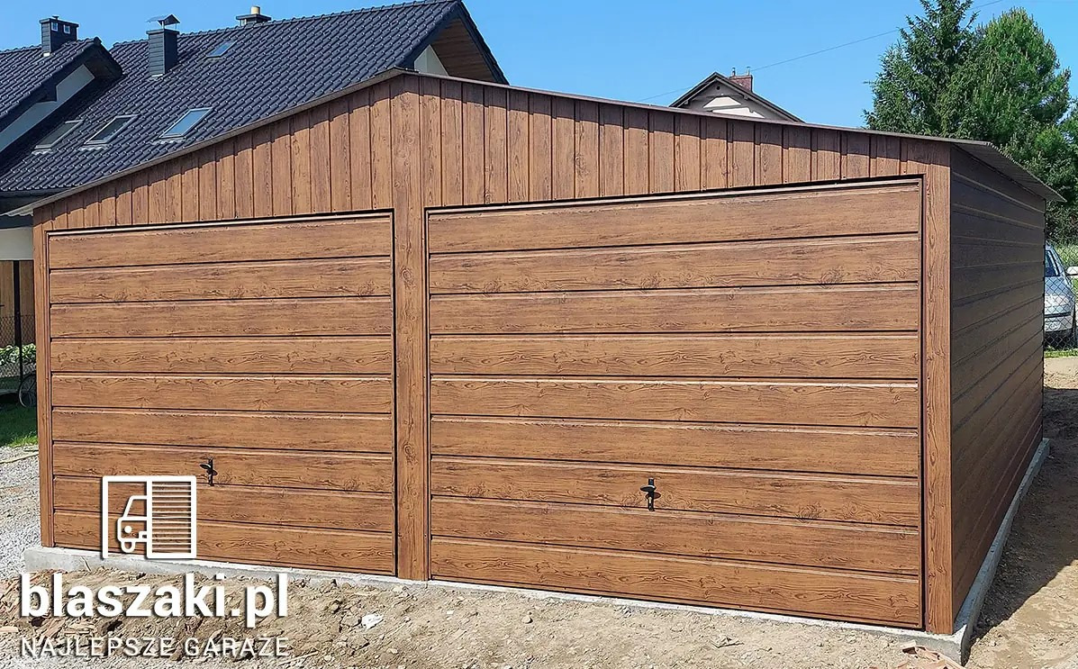 Dwustanowiskowy garaż blaszany z imitacją drewna, z dwuspadowym dachem, na betonowej wylewce, z logo firmy w lewym dolnym rogu.