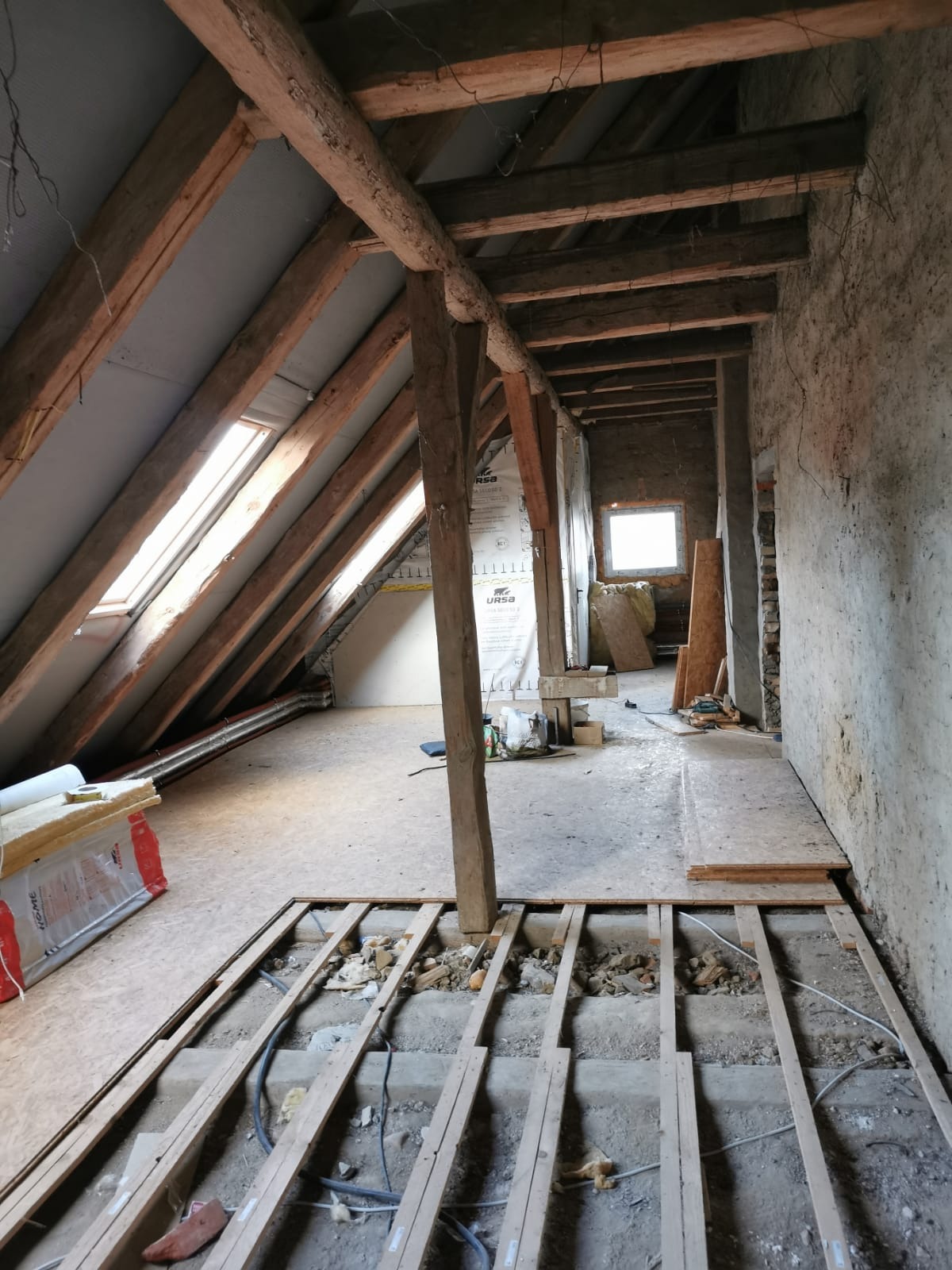 Adaptacja poddasza w Szczecinie: widok na drewnianą konstrukcję dachu, okna połaciowe i przygotowane podłoże pod podłogę. Etap prac wykończeniowych.