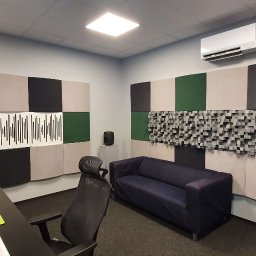 Pro Acoustic Ireneusz Tolak - Profesjonalne studio nagrań z panelami akustycznymi w odcieniach szarości, zieleni i beżu. Widoczny sprzęt audio, biurko i sofa. Klimatyzacja na ścianie.