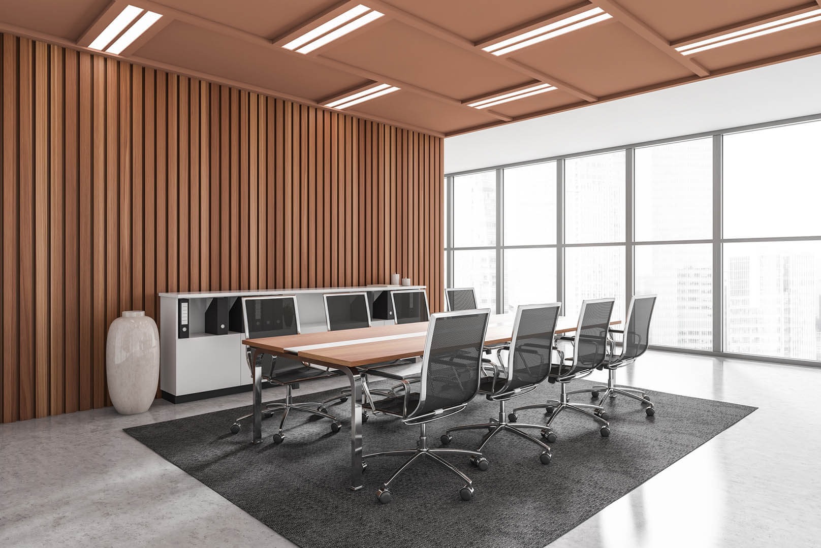 Nowoczesna sala konferencyjna z drewnianą ścianą, dużym oknem i długim stołem na dywanie. Minimalistyczny design z elementami biurowymi i dekoracyjną wazą.