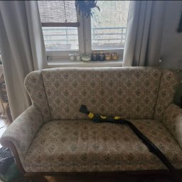 bluestart.kak - Wnętrze z sofą w kwiaty czyszczoną parowo. Dysza parowa na siedzisku, okno w tle. Widoczne ślady czyszczenia.