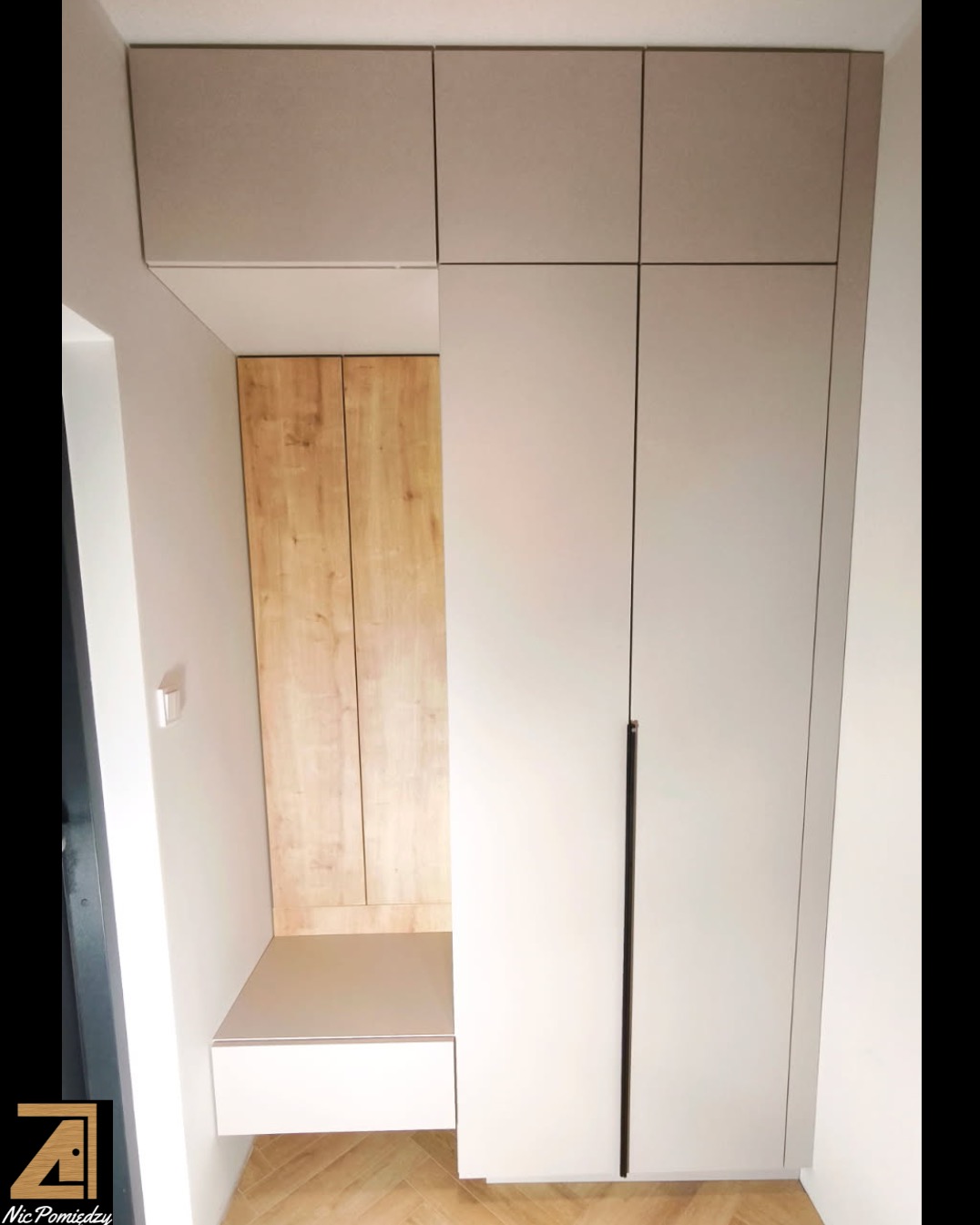 Szafa wnękowa z siedziskiem i szafkami wiszącymi, wykonana na wymiar w Sochaczewie. Jasne fronty, drewniane wykończenie wnęki, minimalistyczny design.