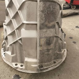 ELASER - Metalowa obudowa, w połowie oczyszczona, ukazująca kontrast przed i po zabiegu. Widoczne detale konstrukcji i różnica w fakturze powierzchni.