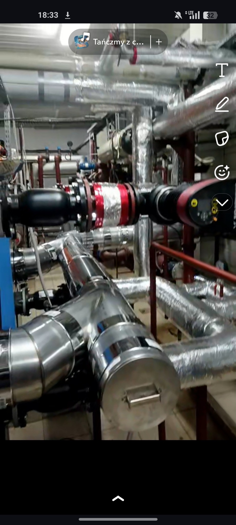 Złożona instalacja rur z izolacją termiczną, widoczne elementy metalowe i zawory. Różne kąty ułożenia rur tworzą skomplikowany system.