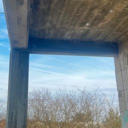 Ziolopol - Surowy betonowy szkielet budynku w trakcie budowy, widok z wnętrza na błękitne niebo i drzewa. Widoczne ślady po szalunkach na suficie.