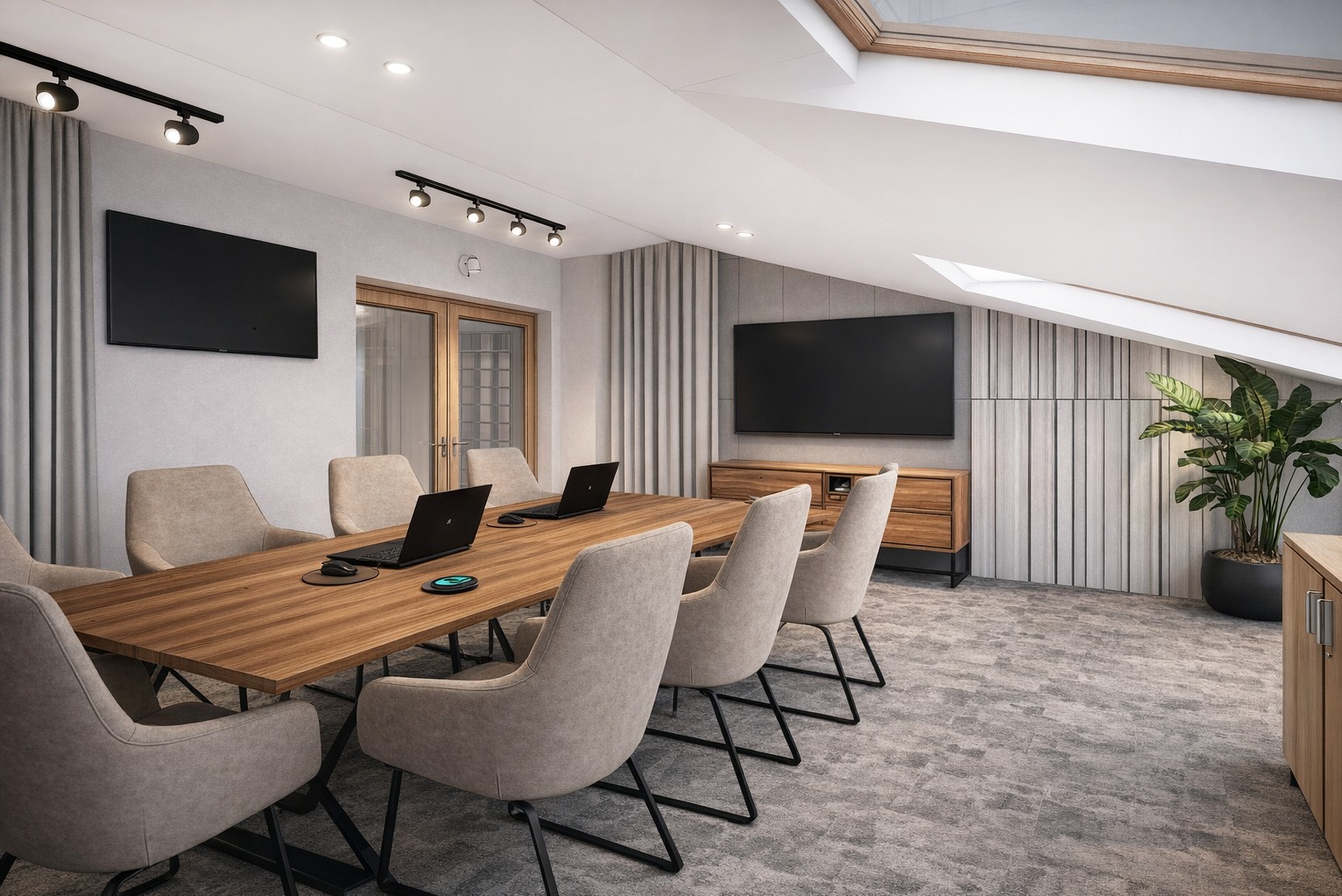 Nowoczesna sala konferencyjna na poddaszu z drewnianym stołem, krzesłami, dwoma telewizorami i rośliną doniczkową. Widoczne okno dachowe i oświetlenie punktowe.