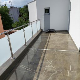 WichBUD Piotr Nochowicz - Balkon z posadzką żywiczną w Obornikach, wykończony szklaną balustradą i metalowymi elementami. Widoczne refleksy światła na gładkiej powierzchni posadzki.