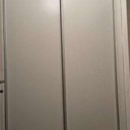 Franciszek Mętel - Minimalistyczna szafa wnękowa z przesuwnymi drzwiami w odcieniach bieli i szarości, zrealizowana w Zawoi. Proste linie, nowoczesny design.