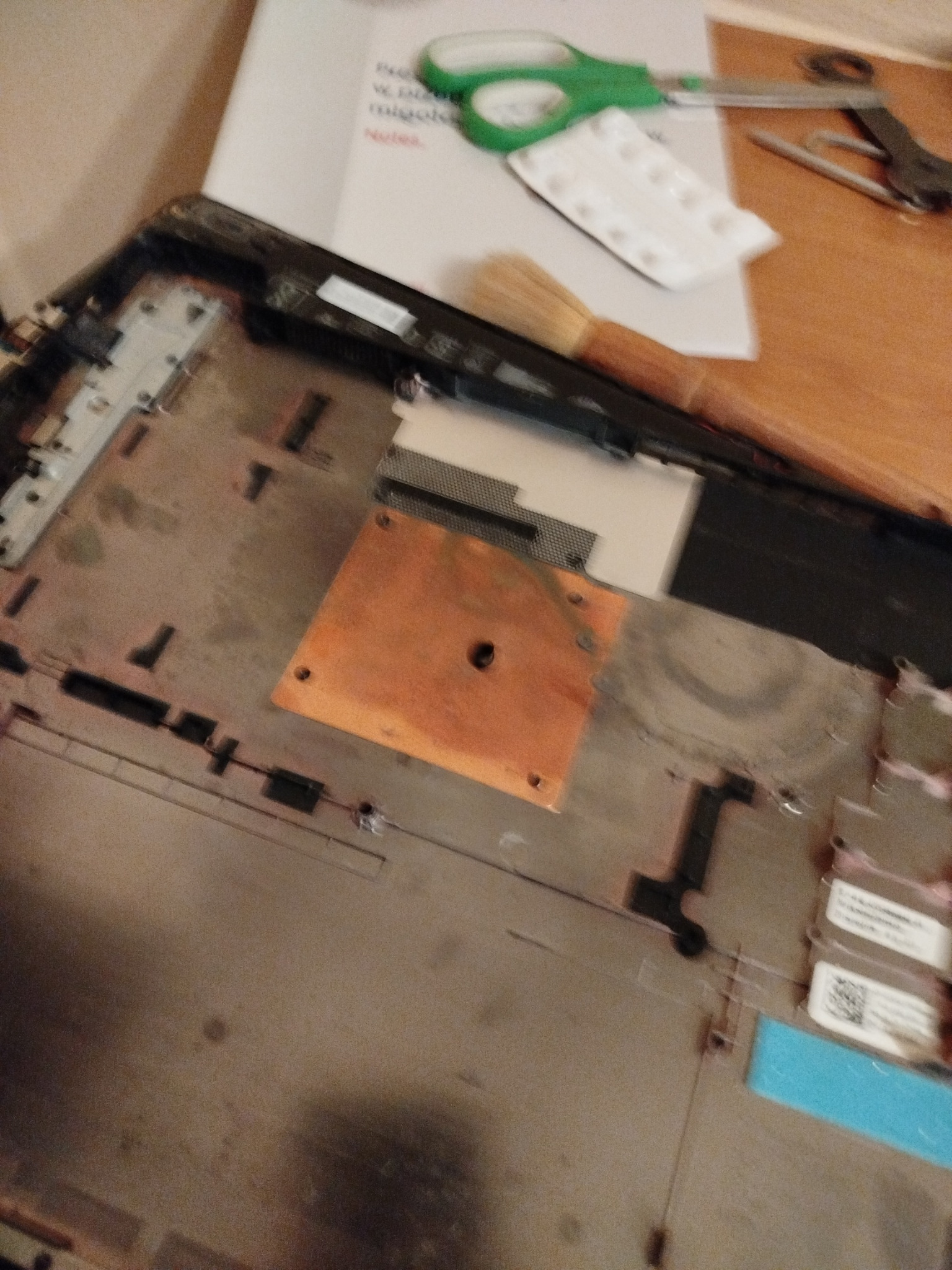 Otwarty laptop z widocznym układem chłodzenia, narzędzia obok. Detal naprawy płyty głównej, widoczna miedziana płytka termiczna i elementy elektroniki. Sprzęt gotowy do serwisu.