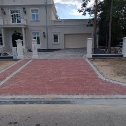 VOLODYMYR DIDUKH - Ukończony podjazd z czerwonej kostki brukowej prowadzący do eleganckiego domu z beżową elewacją i garażem. Widoczne kolumny i elementy dekoracyjne.