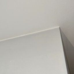 Perfect Walls Adam Andruch - Biały róg pokoju, gdzie ściana łączy się z sufitem. Minimalistyczne ujęcie detalu wykończenia wnętrza, ukazujące precyzję łączenia powierzchni.