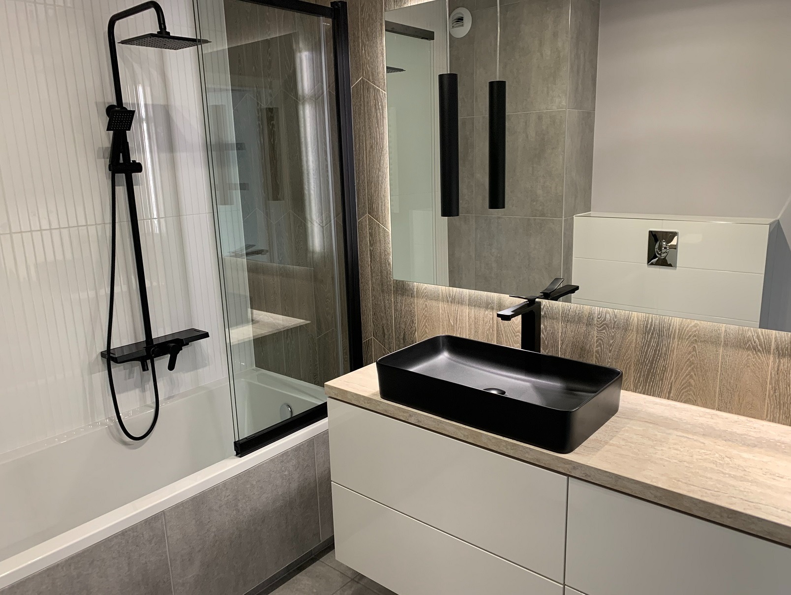 Nowoczesna łazienka w Raba Wyżna z czarną armaturą i umywalką nablatową. Kabina prysznicowa ze szklaną ścianką i grafitowymi profilami. Minimalistyczny design.