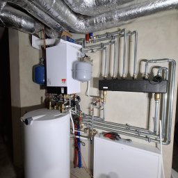 Piotr Sikora - Kompletna instalacja kotła grzewczego Viessmann z zasobnikiem, orurowaniem i izolacją termiczną w pomieszczeniu technicznym. Widoczne elementy instalacji CO.