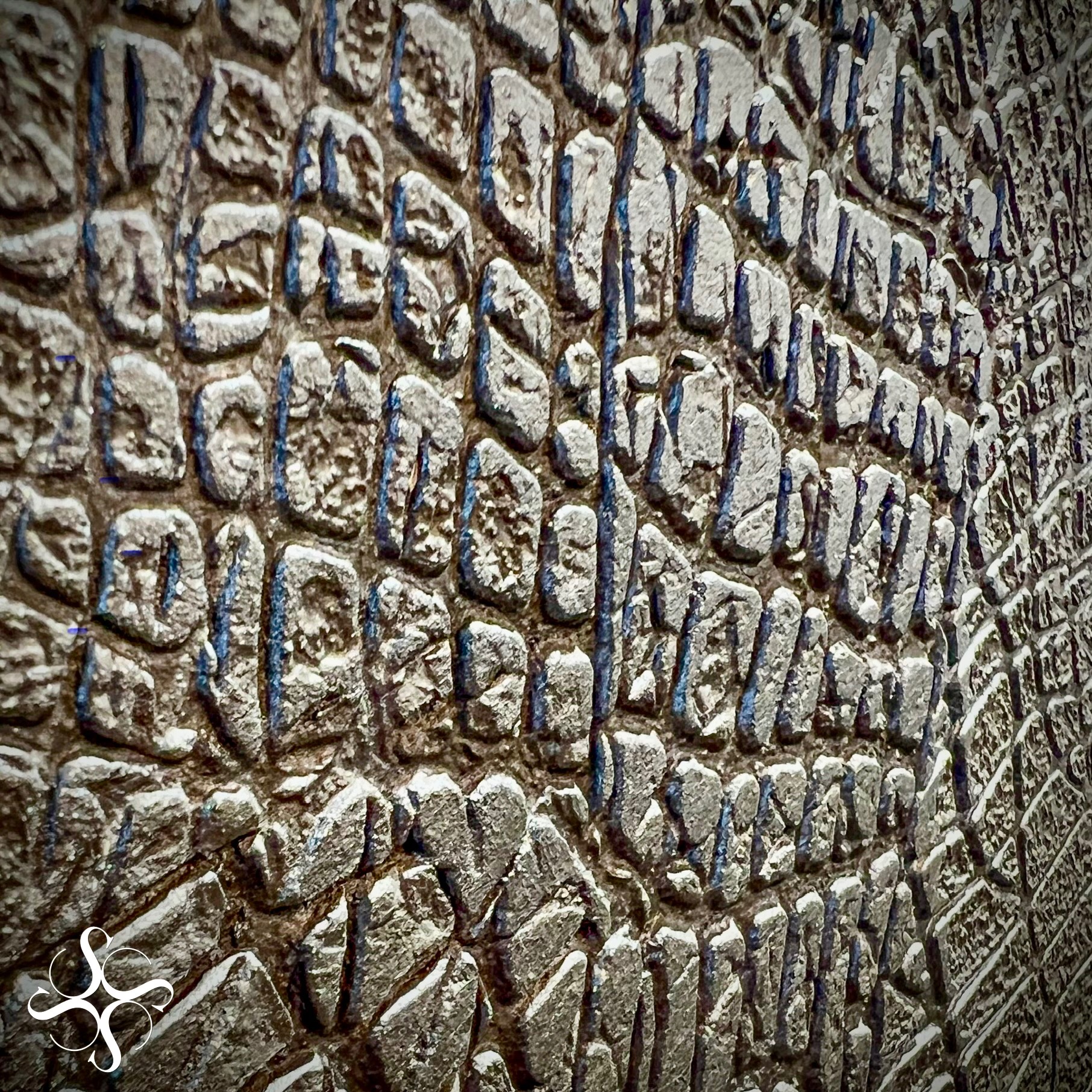 Dekoracyjna ściana z efektem 3D, imitująca kamień w odcieniach szarości i srebra, z wyraźną fakturą i głębią, oświetlona z boku, tworząca ciekawy wzór.