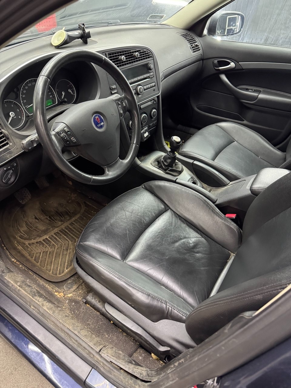 Wnętrze samochodu Saab przed czyszczeniem w Mysłowicach. Widoczne zabrudzone skórzane fotele, dywaniki i deska rozdzielcza. Detailing wnętrza.