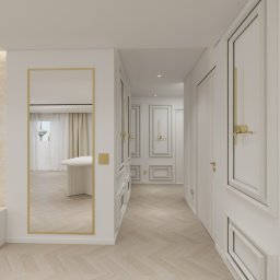 Lumi Interior - Eleganckie wnętrze: białe ściany z dekoracyjnymi listwami, parkiet w jodełkę, złote akcenty na drzwiach i lustrze. W tle widoczny stół i okno.