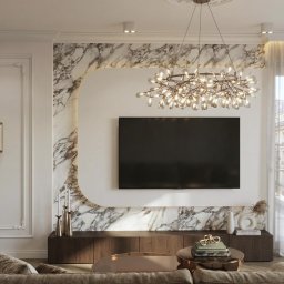 M2 Projekt - Elegancki salon z marmurowym akcentem, nowoczesnym oświetleniem i telewizorem. Widok na miasto przez okno z delikatnymi firanami. Subtelne dekoracje i ciepła kolorystyka.