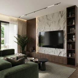 M2 Projekt - Stylowy salon z zieloną sofą narożną, ścianą z kamienia dekoracyjnego i oświetleniem punktowym. Minimalistyczny stolik kawowy i regał z dekoracjami dopełniają aranżację.