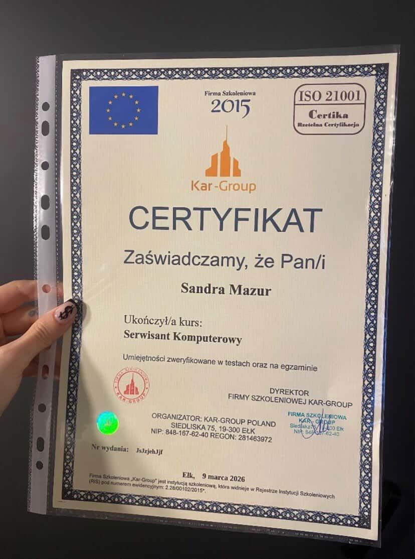 Certyfikat ukończenia kursu serwisanta komputerowego przez Sandrę Mazur, wydany przez Kar-Group, z datą 9 marca 2026. Widoczny hologram i logo firmy.