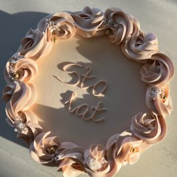 M.S Makaronik - Tort urodzinowy z kremowymi różami i napisem 'Sto lat', dekorowany perłowymi i złotymi kuleczkami, uchwycony w naturalnym świetle z góry.