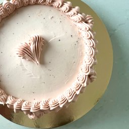 M.S Makaronik - Tort z kremem w odcieniach różu, dekorowany w kształcie serca, na złotej podkładce. Widok z góry, delikatne światło.