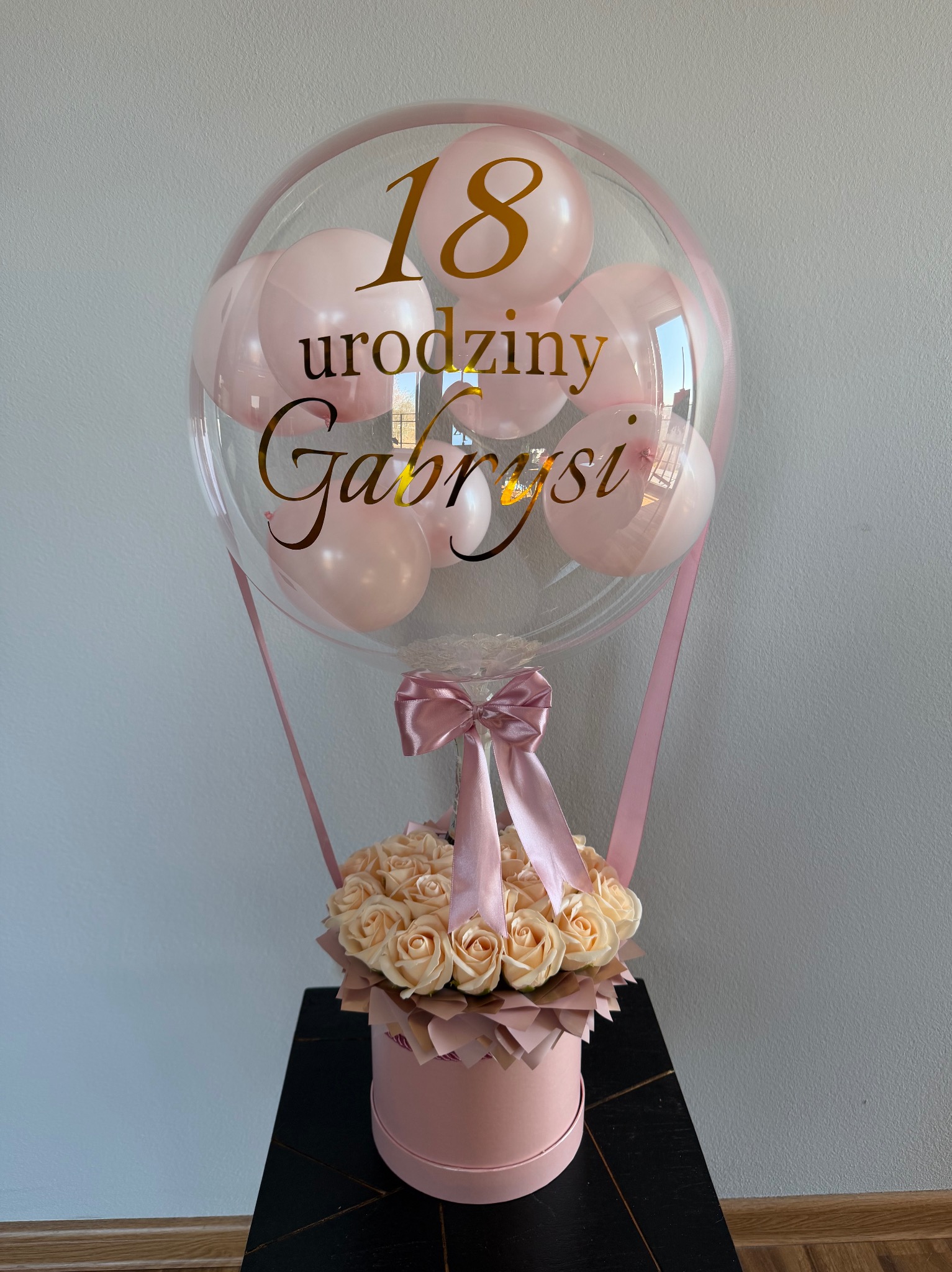 Różowy box z różami i balonem z napisem '18 urodziny Gabrysi', przewiązany wstążką. Prezent na osiemnaste urodziny w pastelowej kolorystyce.